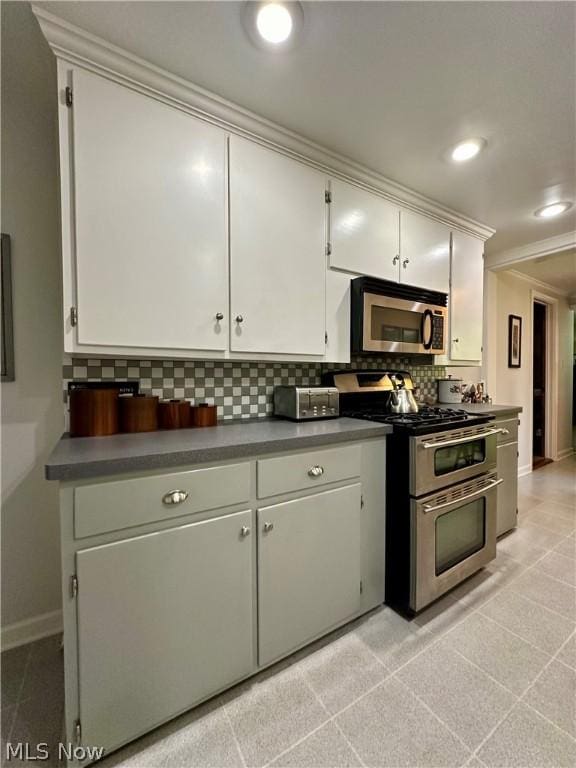 kitchen featuring backsplash, crown molding, white cabinetry, and stainless steel appliances