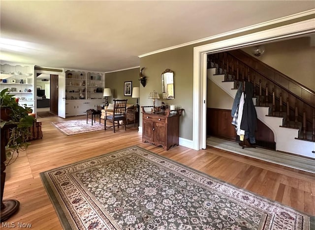 living room with built in shelves, light wood-type flooring, and crown molding