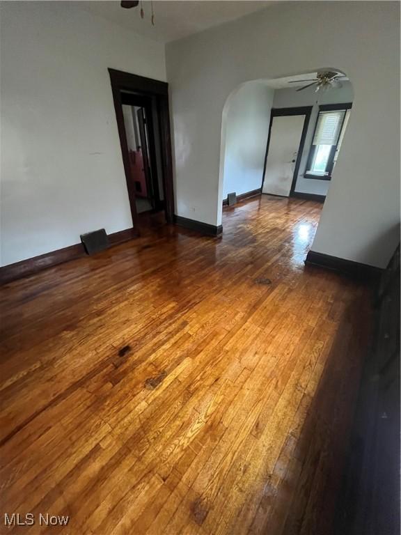 2936 E 128th St, Cleveland, OH 44120 - empty room with a ceiling fan, arched walkways, wood-type flooring, and baseboards