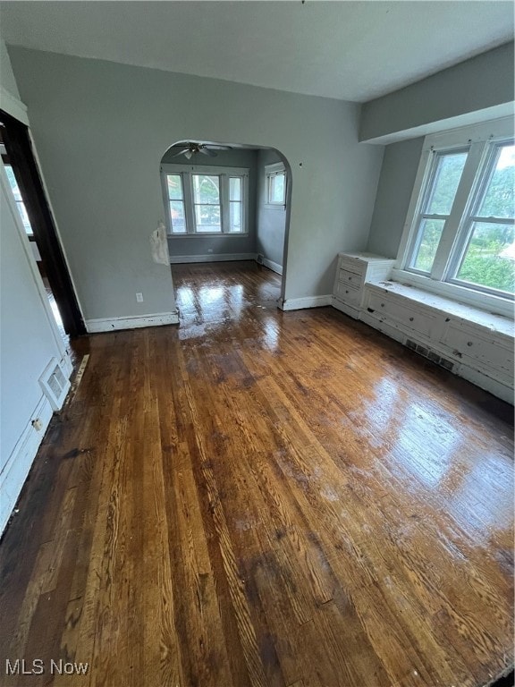 unfurnished living room with ceiling fan and dark wood-type flooring