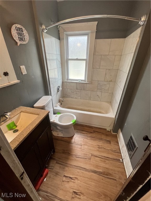 full bathroom featuring toilet, tiled shower / bath combo, vanity, and wood-type flooring