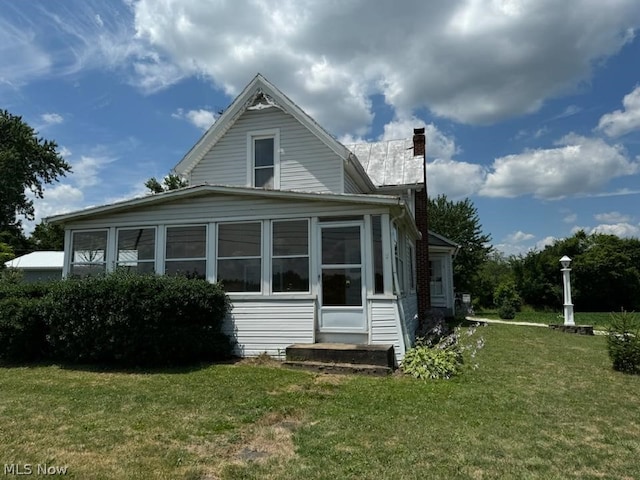 back of property with a lawn and a sunroom