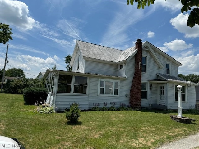 view of property exterior with a lawn and a sunroom