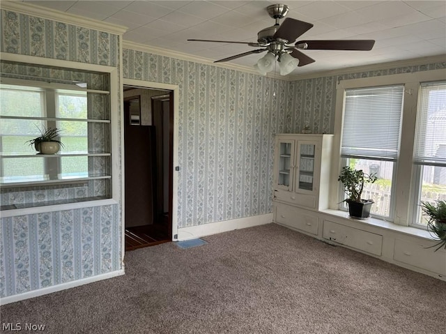 carpeted spare room featuring a wealth of natural light, crown molding, and ceiling fan