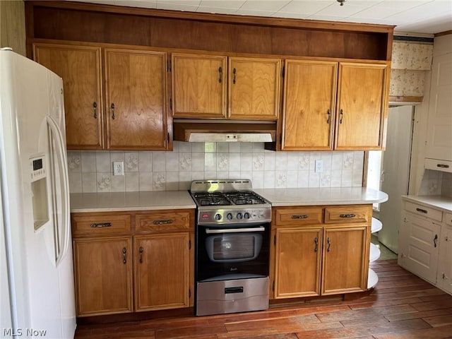 kitchen featuring gas stove, dark hardwood / wood-style flooring, white fridge with ice dispenser, and tasteful backsplash