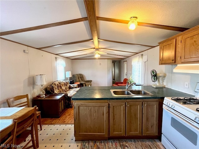 kitchen with sink, ceiling fan, gas range gas stove, beam ceiling, and kitchen peninsula