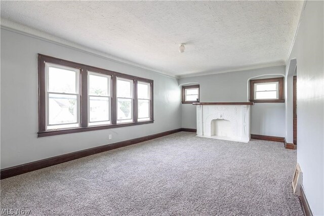 unfurnished living room with carpet flooring, a textured ceiling, a fireplace, and ornamental molding