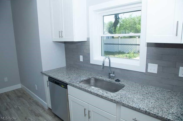 kitchen featuring white cabinetry, dishwasher, sink, light stone counters, and decorative backsplash