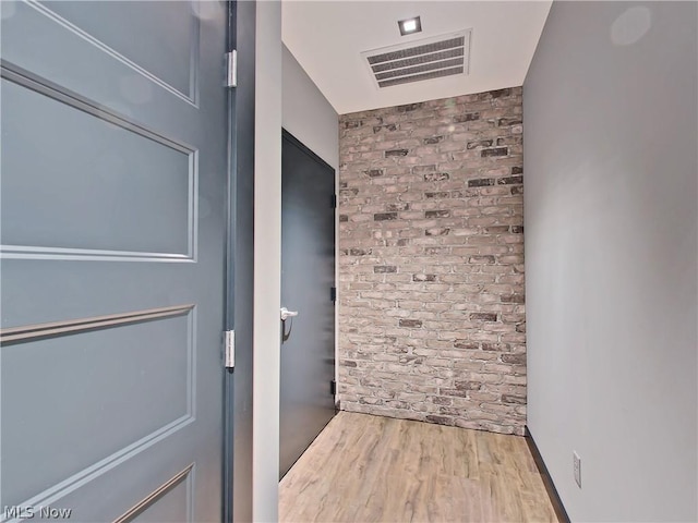 interior space with hardwood / wood-style floors and brick wall