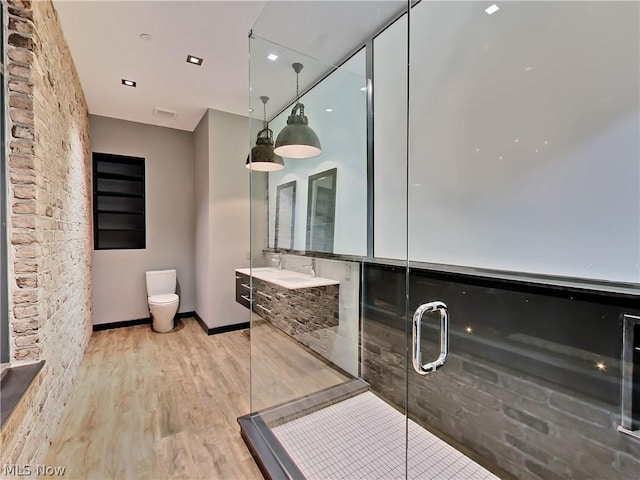bathroom featuring toilet, vanity, a shower with door, and wood-type flooring