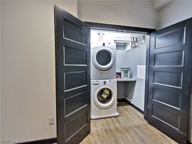 washroom featuring stacked washer / drying machine and light hardwood / wood-style flooring