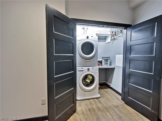 laundry room with wood-type flooring and stacked washer and dryer