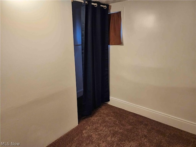 spare room featuring dark carpet