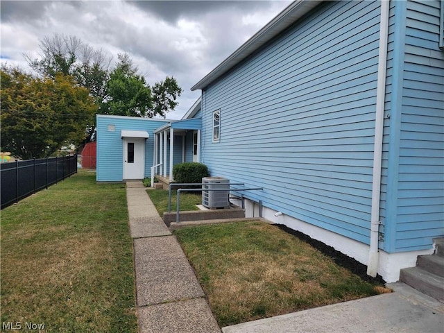 view of side of property featuring an outdoor structure, a lawn, and central air condition unit