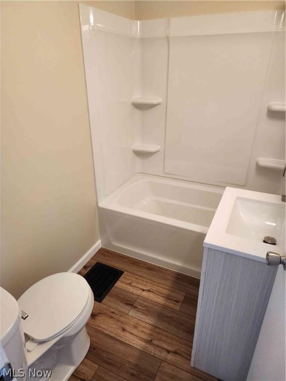 full bathroom with hardwood / wood-style flooring, vanity, washtub / shower combination, and toilet