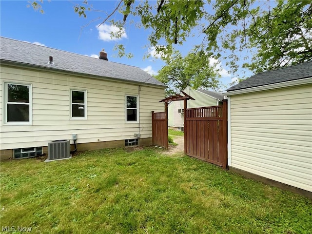 rear view of property featuring cooling unit, a pergola, and a lawn