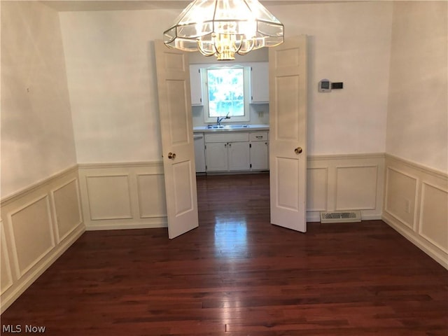 unfurnished dining area featuring dark hardwood / wood-style floors, an inviting chandelier, and sink