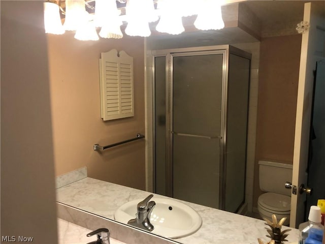 bathroom featuring vanity, toilet, an enclosed shower, and a notable chandelier