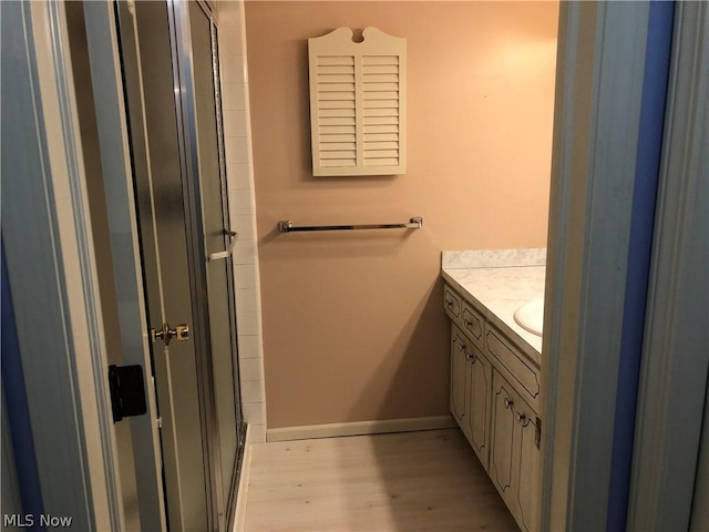 bathroom featuring hardwood / wood-style flooring, vanity, and a shower with door