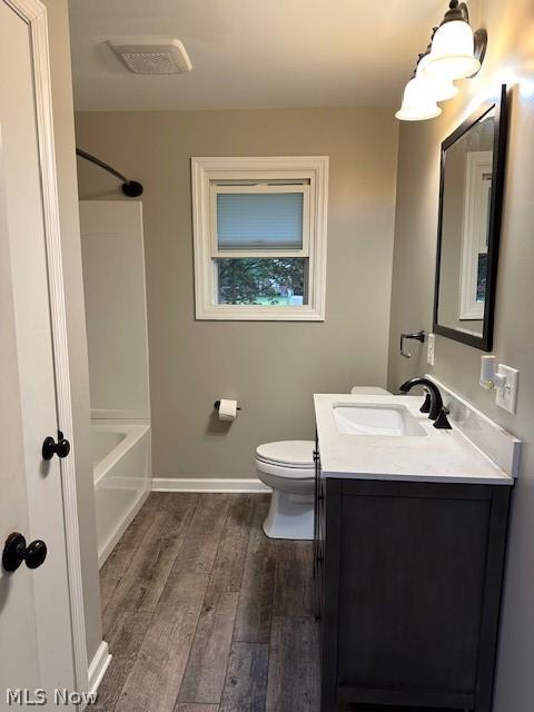 full bathroom featuring hardwood / wood-style flooring, vanity, toilet, and bathing tub / shower combination