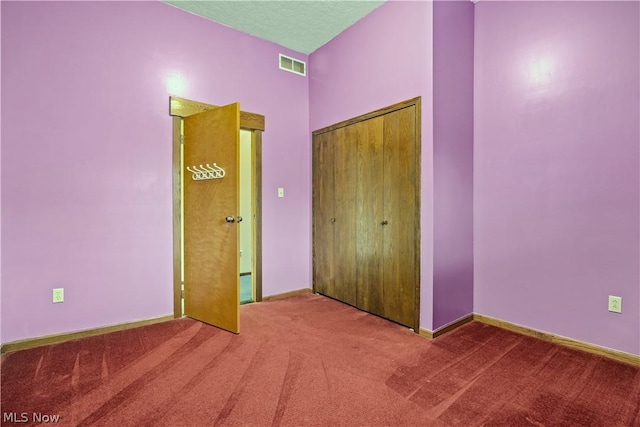 unfurnished bedroom with carpet flooring, a textured ceiling, and a closet