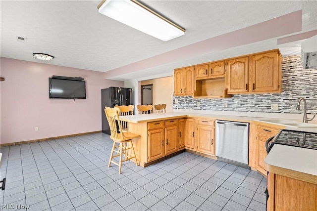 kitchen with sink, kitchen peninsula, a breakfast bar area, decorative backsplash, and black appliances