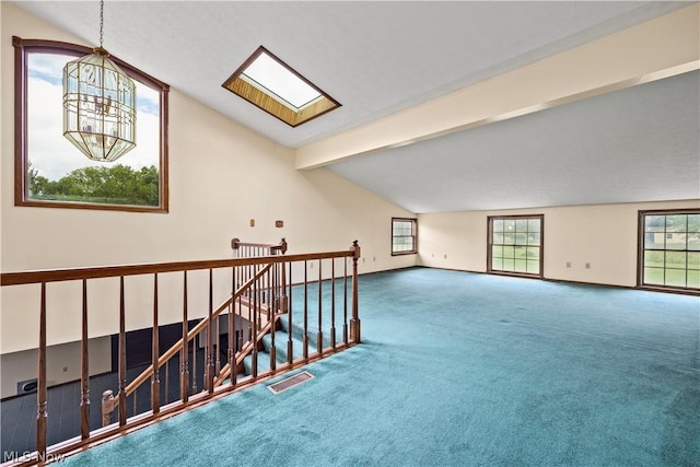 spare room featuring a chandelier, carpet flooring, and lofted ceiling with skylight