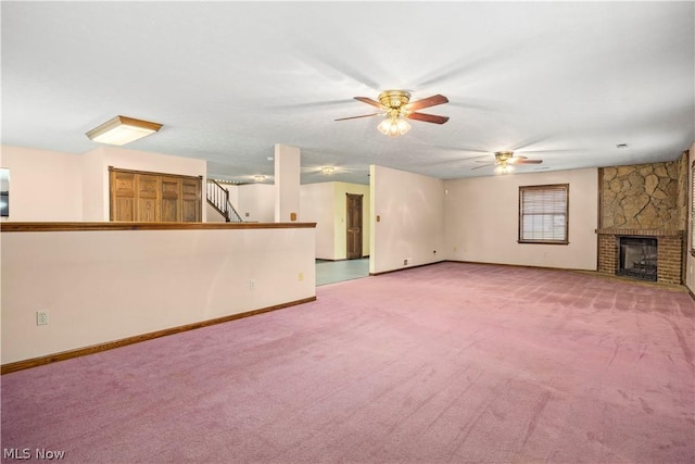 unfurnished living room with ceiling fan, a fireplace, and light carpet