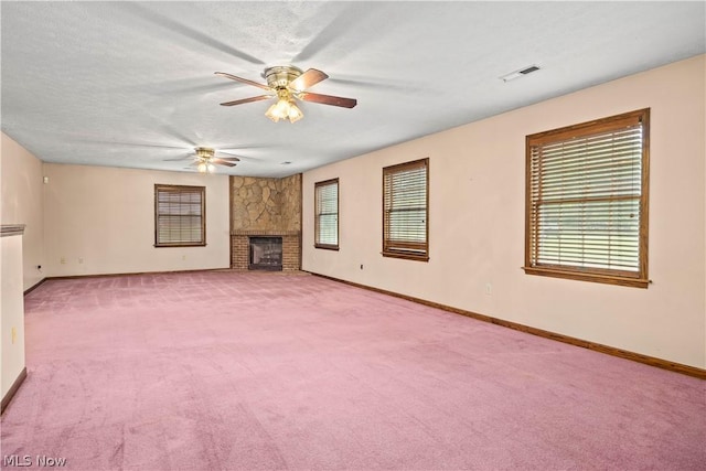 unfurnished living room with a stone fireplace, ceiling fan, light colored carpet, and a textured ceiling