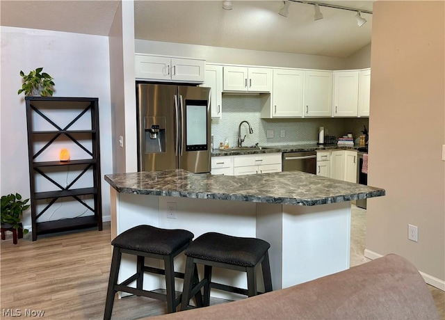 kitchen featuring sink, appliances with stainless steel finishes, backsplash, a kitchen breakfast bar, and white cabinets