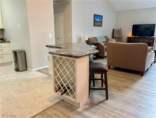 kitchen featuring lofted ceiling, a breakfast bar area, and light hardwood / wood-style flooring