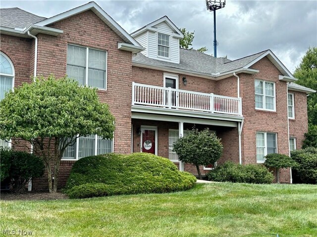 townhome / multi-family property featuring a balcony and a front yard