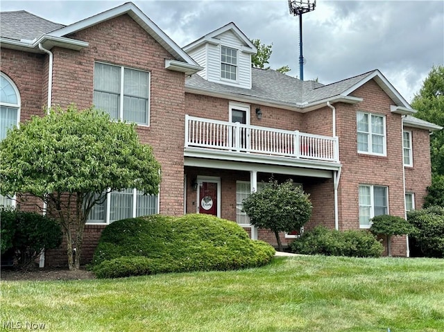 townhome / multi-family property featuring a balcony and a front lawn