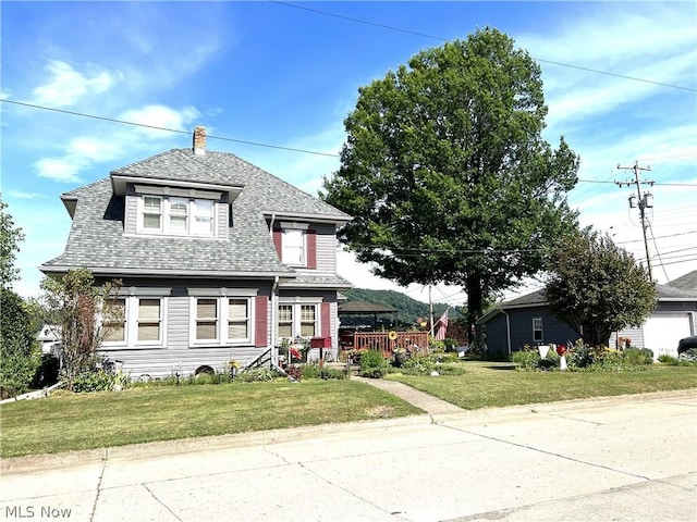 view of front facade with a front lawn and a shingled roof