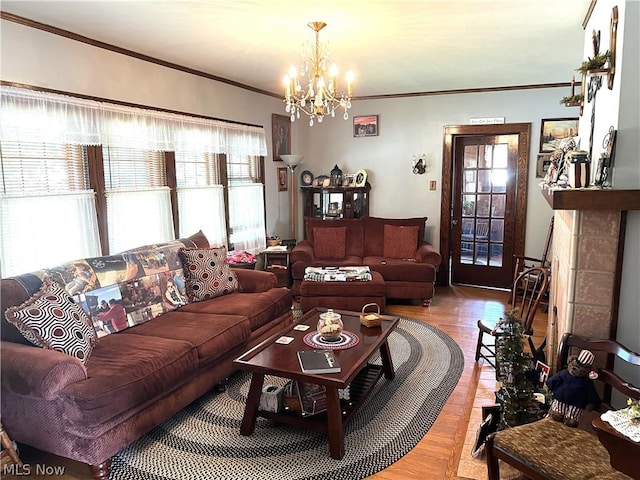 living area featuring a notable chandelier, wood finished floors, crown molding, and a tile fireplace