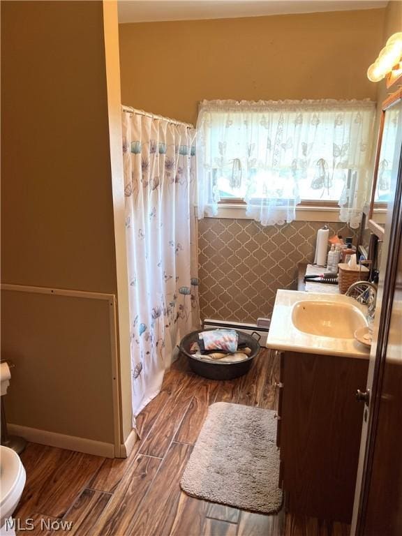 full bathroom with a shower with shower curtain, wood finished floors, vanity, and baseboards