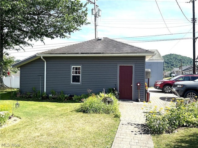 exterior space featuring a shingled roof and a front yard