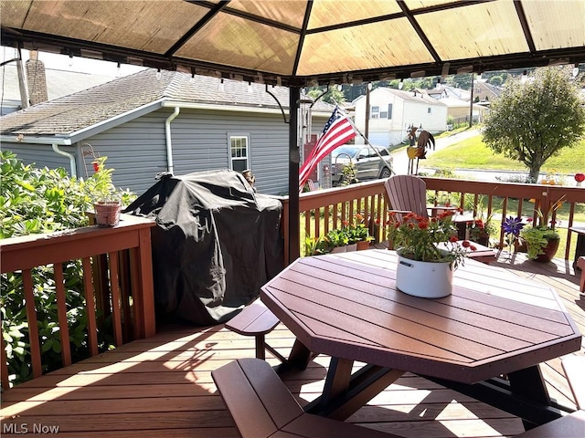 wooden terrace featuring a gazebo and outdoor dining area