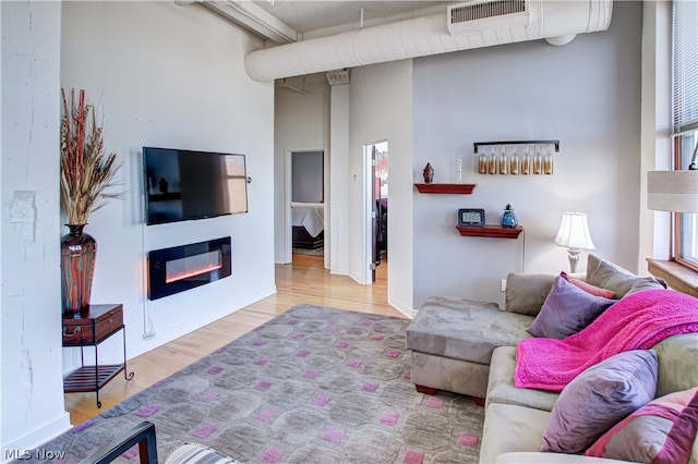 living room with beamed ceiling, hardwood / wood-style flooring, plenty of natural light, and a towering ceiling