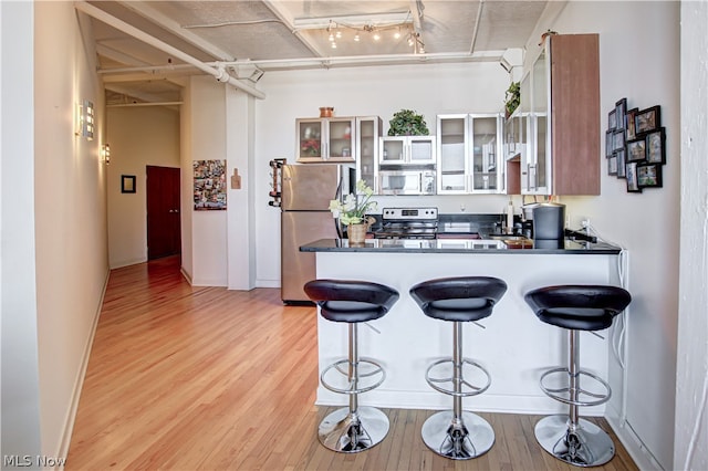 kitchen with kitchen peninsula, light hardwood / wood-style flooring, stainless steel appliances, and a breakfast bar