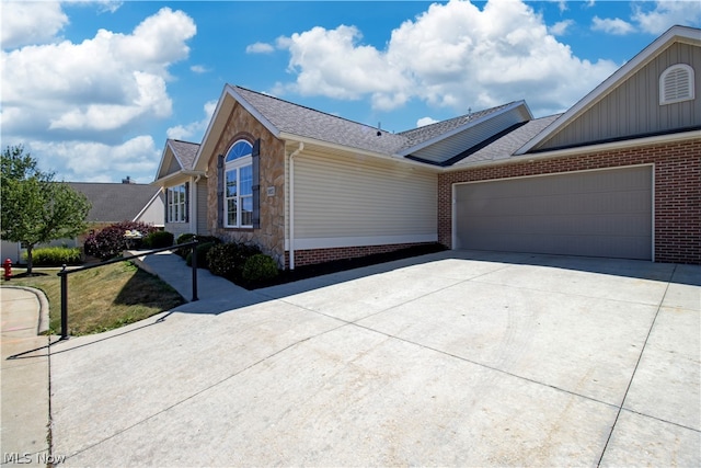 view of front facade with a garage, stone siding, concrete driveway, and brick siding