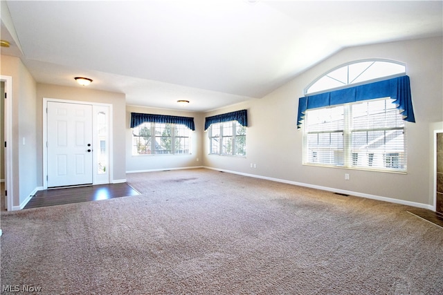 foyer featuring lofted ceiling and dark colored carpet