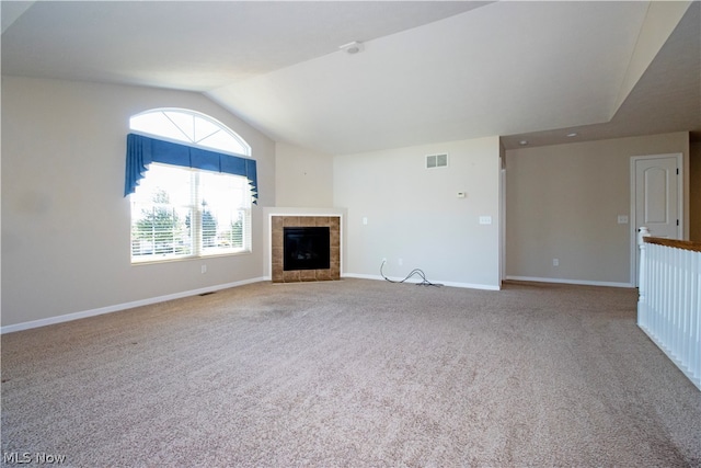 unfurnished living room featuring baseboards, visible vents, a tiled fireplace, carpet, and vaulted ceiling