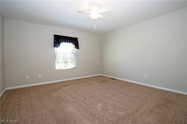 unfurnished room with a ceiling fan, carpet, and baseboards