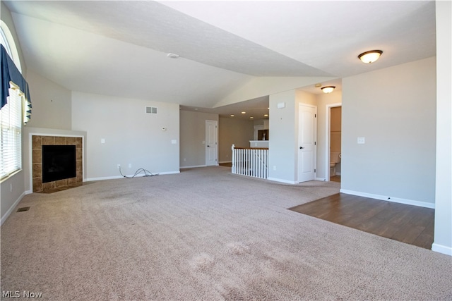 unfurnished living room featuring baseboards, visible vents, lofted ceiling, carpet flooring, and a fireplace