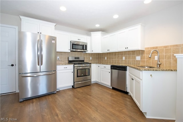 kitchen with tasteful backsplash, appliances with stainless steel finishes, dark wood-type flooring, white cabinets, and a sink