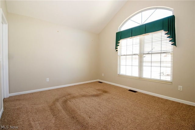 empty room featuring lofted ceiling, baseboards, visible vents, and carpet flooring