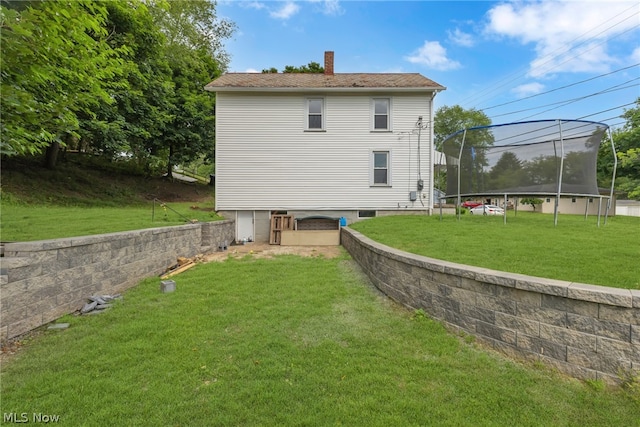 back of property with a trampoline and a yard