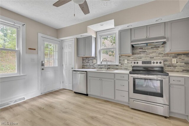 kitchen with sink, ceiling fan, stainless steel appliances, and light hardwood / wood-style floors