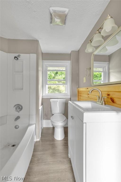 full bathroom featuring washtub / shower combination, a textured ceiling, toilet, vanity, and hardwood / wood-style flooring